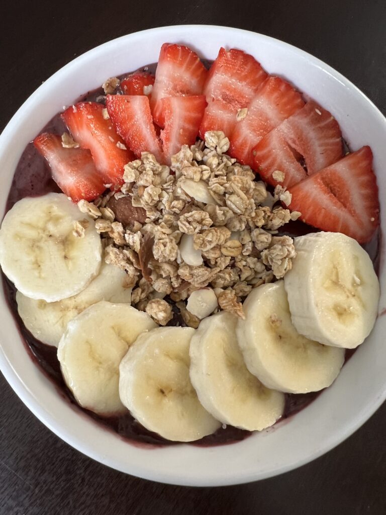 acai bowl topped with granola, bananas, and strawberries